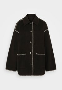 Czarna zamszowa kurtka o luźnym kroju, z dużym kołnierzem, białymi kontrastującymi szwami, dużymi kieszeniami z przodu i zapięciem na guziki.