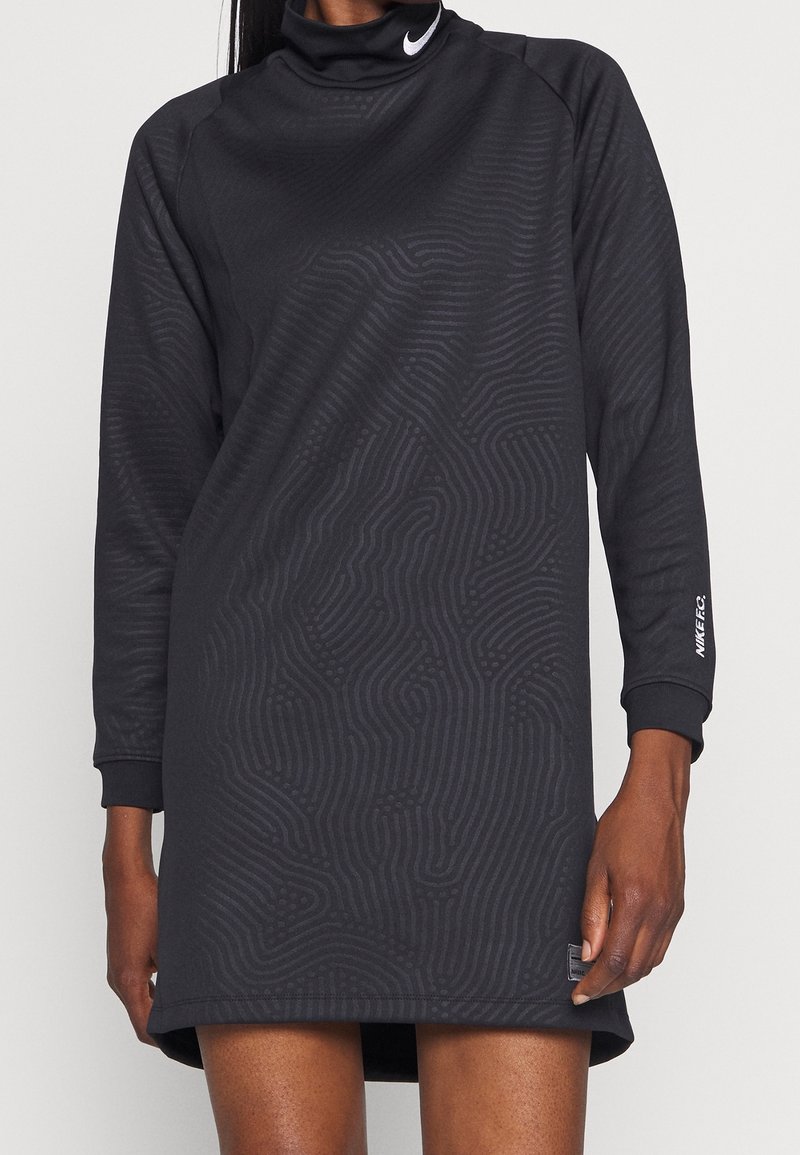 Musta pitkähihaisista mekko korkealla kauluksella, tekstuuripinta-aallot ja Nike-logo hihassa. Valmistettu pehmeästä ja joustavasta kankaasta.
