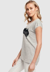 Hellgrau T-Shirt mit kurzen Ärmeln, das eine schwarze Umrisskarte von Australien und den Text "AUSTRALIEN" zeigt. Weicher Stoff mit lässiger Passform.