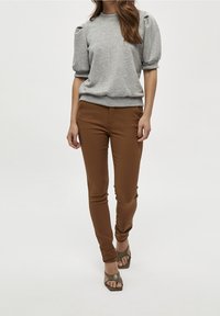 Grå sweatshirt med puffärmar, matchad med bruna tajta byxor och gröna sandaletter med öppen tå. Enkel, avslappnad design med ribbade manschetter.