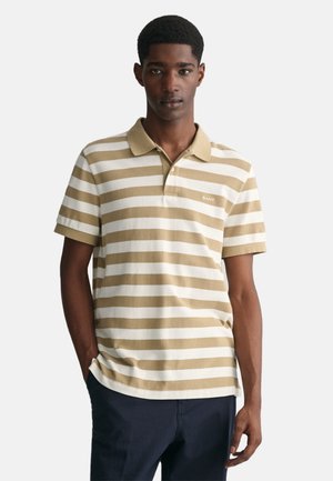 Camisa polo de rayas beige y blanca con mangas cortas, cuello abotonado y un pequeño logo en el pecho, confeccionada en suave material de algodón.