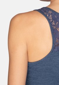 Top senza maniche in tessuto blu scuro, con un design della schiena in pizzo. Texture liscia con bordi arrotondati sulle spalle e sulla schiena.