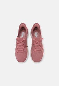 Pink mesh athletic shoes with a textured surface, featuring flat laces and a cushioned sole, designed for slip-on convenience.