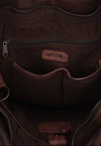 Dark brown leather bag interior with multiple pockets, a zipper compartment, and a stitched label reading "Quali Leather."