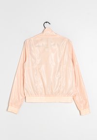 Béžová, lesklá bomber bunda s elastickými manžetami a lemem, vybavená zipem a vyrobená z hladkého, lehkého materiálu.