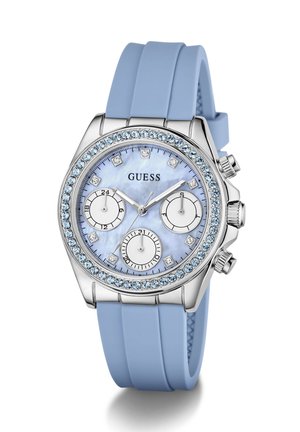 Ura Guess z ohišjem srebrne barve, svetlomodrim kristalnim okvirjem, svetlomodrim silikonskim trakom in tremi podštevilčnicami na svetlomodni številčnici.