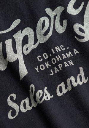 Tela negra con texto de estilo vintage en blanco y gris que incluye "Super" y "Sales and", junto con texto adicional que indica detalles de la empresa.