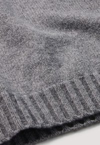 Grau gestrickter Stoff mit einer weichen Textur, der einen gerippten Saum aufweist. Das Material ist leicht und weist ein dezentes Muster auf.