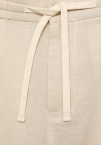 Beige linnen joggers met een elastische tailleband, zijzakken en een gestructureerde stofafwerking. Eenvoudige en functionele ontwerpdetails.
