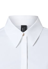 Weißes Hemd mit klassischem Kragen, vorderer Knopfverschluss mit einem goldfarbenen Knopf und schwarzem Markenlabel am Halsausschnitt.