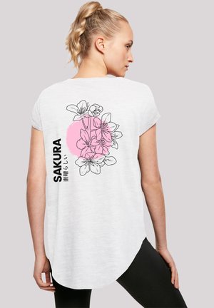 Weißes T-Shirt mit kurzen Ärmeln, das mit einem floralen Grafikdesign, dem Text "SAKURA", einem rosa Kreis und schwarzer Linienstickerei auf der Rückseite verziert ist. Abgerundeter Saum.