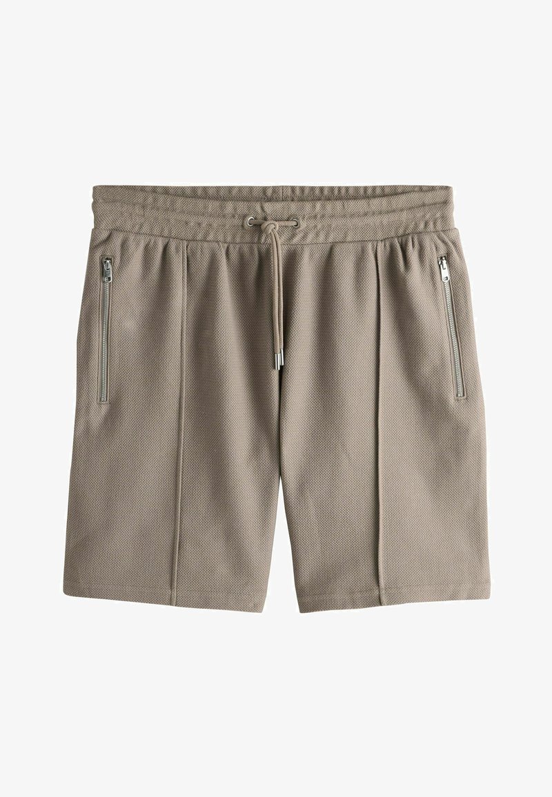 Shorts en tissu beige texturé avec taille élastique, cordon de serrage et poches verticales zippées de chaque côté.