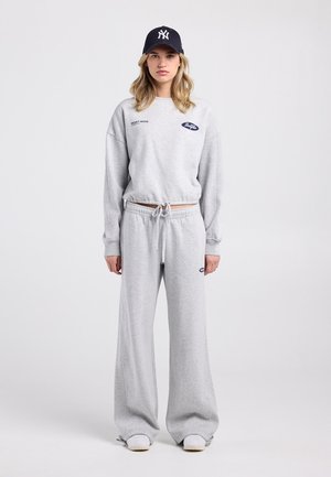 Sweat-shirt gris clair à coupe oversize, arborant le texte « RESET MODE », accompagné d'un pantalon de survêtement ample assorti et d'une casquette marine.