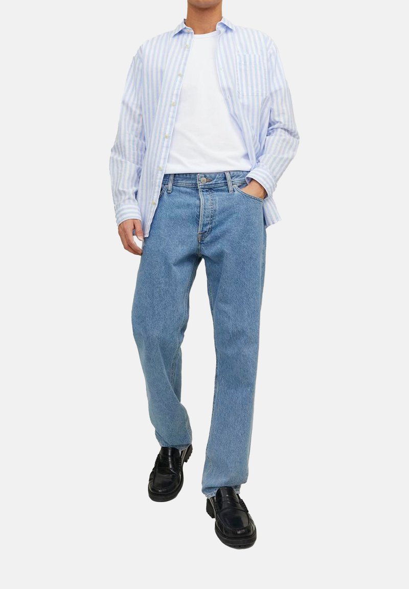 Chemise à rayures bleu clair et blanche avec des boutons, t-shirt blanc, jean droit bleu, et chaussures noires à finition lisse.