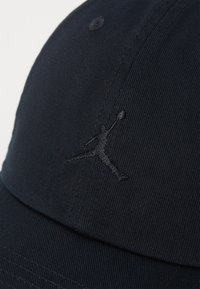 Mornarica kapa za baseball iz teksturiranega blaga, s črnim vezenim Jumpman logotipom spredaj in šivanim vizirjem.