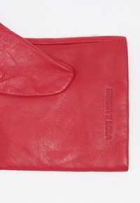 Clutch de cuero rojo con una textura suave, que presenta un cierre de solapa y el nombre de la marca, Bimba y Lola, grabado en el lateral.