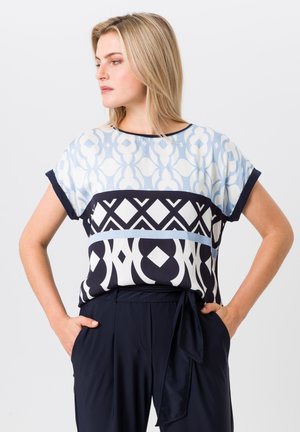 Patterned blouse with short sleeves; features light blue, navy, and white geometric designs; soft fabric with a relaxed fit.