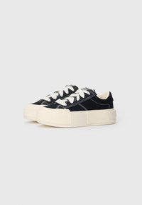 Black high-top sneakers with white stitching and laces, platform sole in cream, rounded toe, and soft fabric upper.