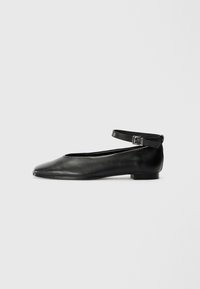 Ballerine in pelle nera con punta affusolata e sottile cinturino alla caviglia, caratterizzate da un tacco basso e una trama liscia. Design semplice e minimale.