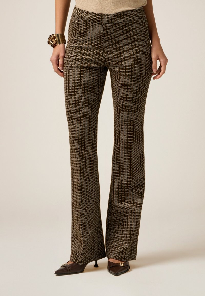 Un pantalon marron à motifs avec une finition texturée, des jambes évasées et une taille haute, associé à des escarpins marron à bout pointu.