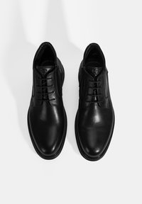 Chaussures de ville en cuir noir avec une finition lisse, bouts ronds et lacets. Présentent un accent cousu autour de la semelle.