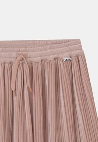 Falda plisada de suave tela rosa con cinturilla elástica y cordón ajustable, que presenta una pequeña etiqueta de la marca.