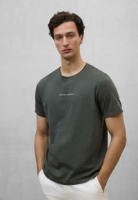 Oliven grøn, kortærmet T-shirt lavet af bl�ødt bomuld, med rund halsudskæring og trykt tekst på forsiden og venstre ærme.