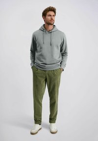 Grijze hoodie met trekkoord, corduroy groene broek en witte sneakers. Casual fit, zachte textuur en geribbelde manchetten op de hoodie.