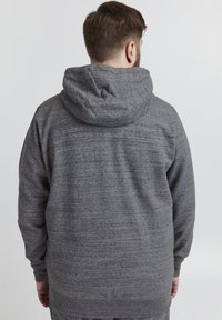 Sudadera con capucha gris, hecha de una tela suave y texturizada, con un bolsillo tipo canguro y puños y dobladillo de canalé. Vista trasera mostrada.
