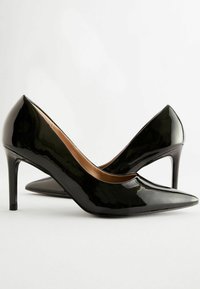 Mustat patenttinaarmokengät, joissa on kärjellinen varvas ja hoikka stiletto-korko. Sileä pinta, jossa on kiiltävä viimeistely ja beigensävyinen sisävuori.