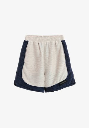 Pantalones cortos de tela texturizada en beige claro y azul marino con cintura elástica, dobladillo curvado y pequeña etiqueta negra en la parte delantera derecha.