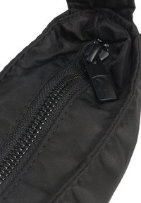 Juodas užtrauktukas dėklas, pagamintas iš lygaus nailono audinio. Yra matomas užtrauktukas su metalinėmis dantimis ir juoduoju traukikliu, su siūtomis briaunomis.