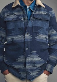 Sako v námořnické modři se vzorem a světle modrými a šedými cik-cak pruhy, s měkkým béžovým límcem, náprsními kapsami a zapínáním na knoflíky. Texturovaná tkanina.