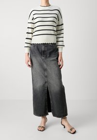 Pull rayé à texture côtelée, avec ourlet festonné, associé à une longue jupe en jean foncé avec une fente avant et deux poches.