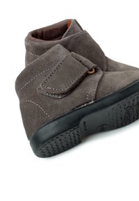 Stivaletti alla caviglia in suede grigio con una cinghia in Velcro, caratterizzati da punta rotonda, cuciture a contrasto e una suola in gomma nera testurizzata.