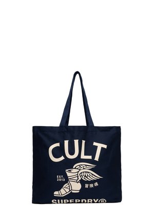 Marine canvas tote bag met twee handvatten, met grote witte tekst "CULT" en een graphic van een gevleugelde laars, opgericht in 2013.