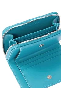 Portafoglio in pelle turchese con chiusura a cerniera, molteplici scomparti per carte e una texture liscia. Presenta dettagli in argento e un design strutturato.