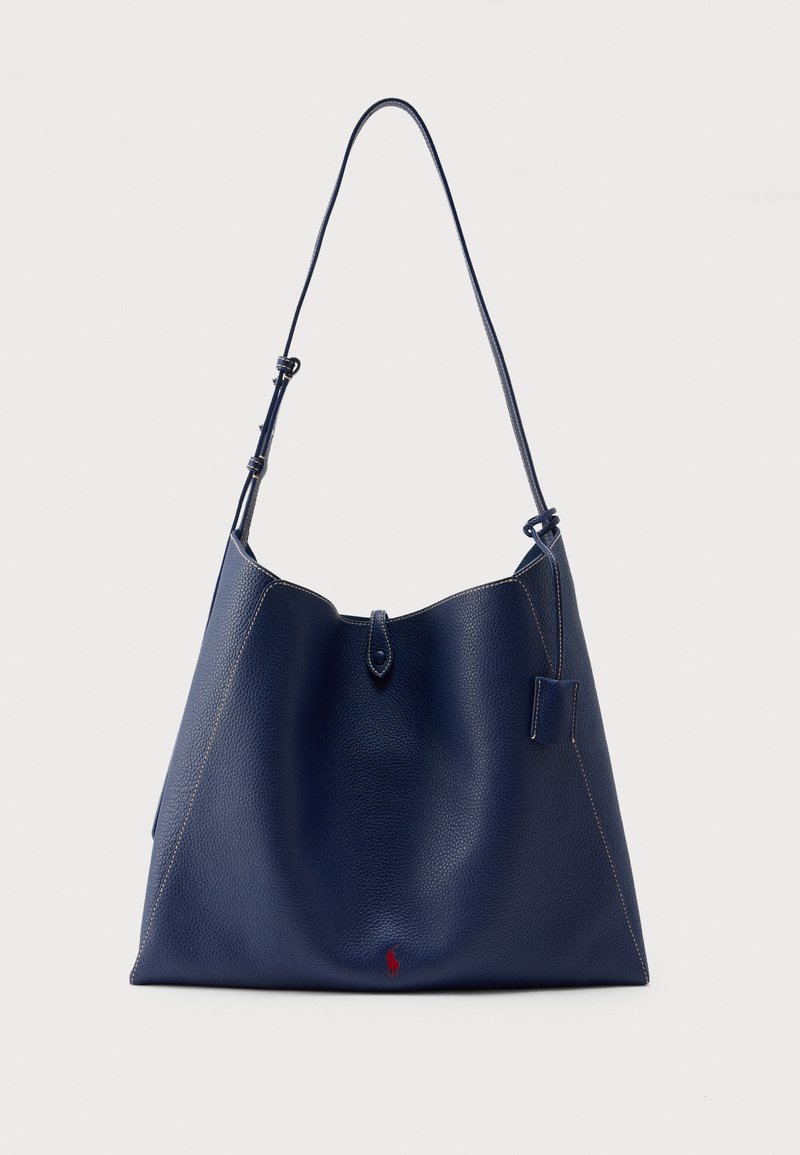Τσαντάκι ώμου από ναυτικό δέρμα με απαλή υφή, ανοιχτή κορυφή και ρυθμιζόμενο λουρί. Διαθέτει αντίθετη ραφή και μικρή κόκκινη λεπτομέρεια με λογότυπο.