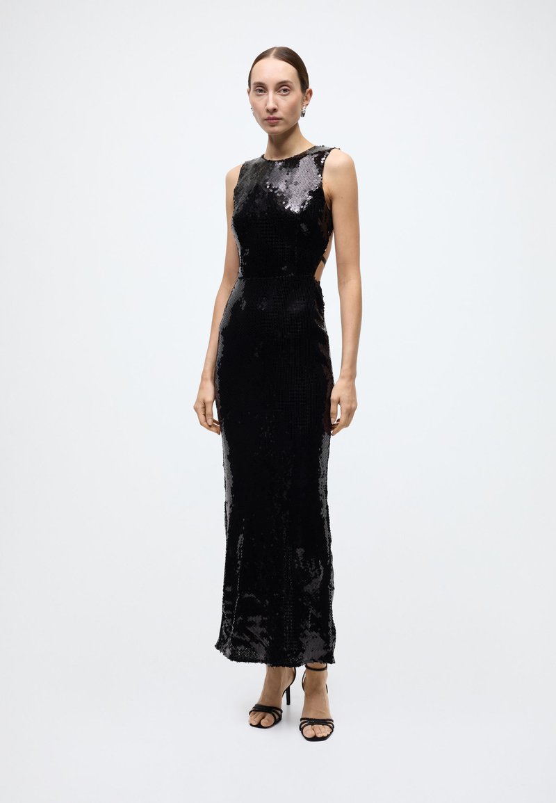 Black sequin evening gown with a sleeveless design and high neckline. Body-hugging fit with side cutouts and a flowing skirt.