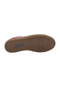 Suola di sneaker in gomma beige con grip testurizzato. Presenta motivi circolari e esagonali. Branding su un'etichetta scura vicino al tallone.