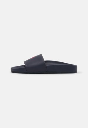 Marineblaue Slipper-Sandale mit strukturierter Fußsohle und einem breiten Riemen oben, seitliche Ansicht auf weißem Hintergrund.