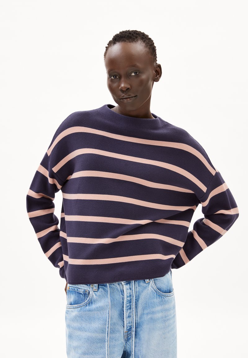 Marineblauw en roze gestreepte trui met een bootnek en verlaagde schouders, gecombineerd met lichtblauwe denim jeans.