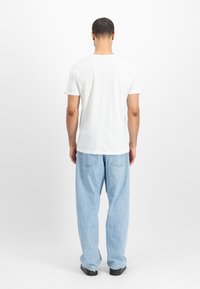 Hvid kortærmet t-shirt med rund hals, parret med lyseblå brede jeans. Enkel design, bomuldsstof, afslappet pasform.