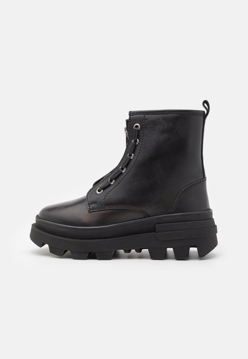 Botas de cuero negras hasta el tobillo con una suela gruesa, que presentan ojales de metal, diseño de cordones y puntera redonda. Suela estriada para mayor tracción.