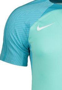 Maglietta sportiva Nike di colore turchese, caratterizzata da un design testurizzato, maniche corte e un logo bianco sul lato sinistro in alto.