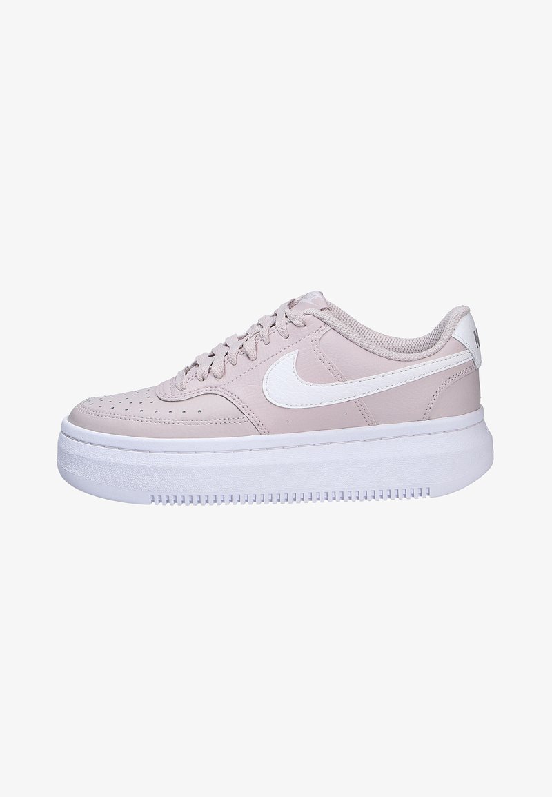Baskets Nike rose clair avec un dessus en cuir lisse, des accents blancs, des détails perforés sur les orteils et une semelle blanche épaisse.