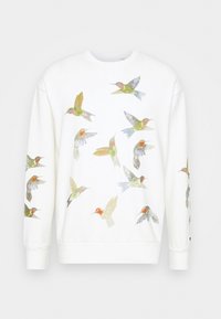 Felpa bianca con disegni colorati di colibrì ricamati in varie posizioni, che mostrano dettagli e trame intricate.