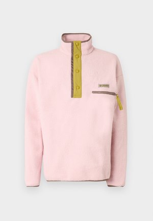 Minkštas rožinis veliūrinis megztinis su garstyčių spalvos sagų užtrauktuku, rudais apvadais ir kišenėle krūtinėje su užtrauktuku, sukurtas dėvėti lauke.