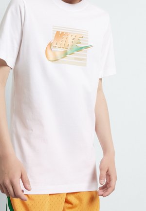 Biała bawełniana koszulka z kolorowym logo Nike zawierającym geometryczne elementy wzornicze na wzorzystym tle. Krótkie rękawy, standardowy krój.