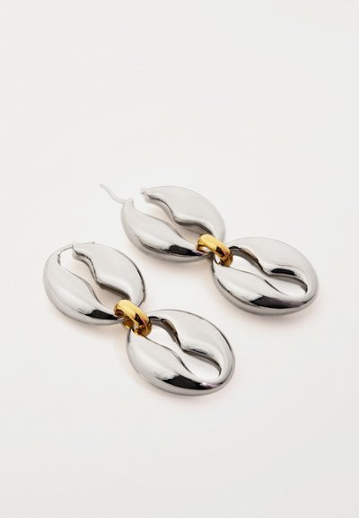 Ασημένια σκουλαρίκια με αλυσίδα σε οβάλ σχήμα και συνδέσμους σε χρυσή απόχρωση, με λείες, καμπυλωτές εγκοπές σε λευκό φόντο.